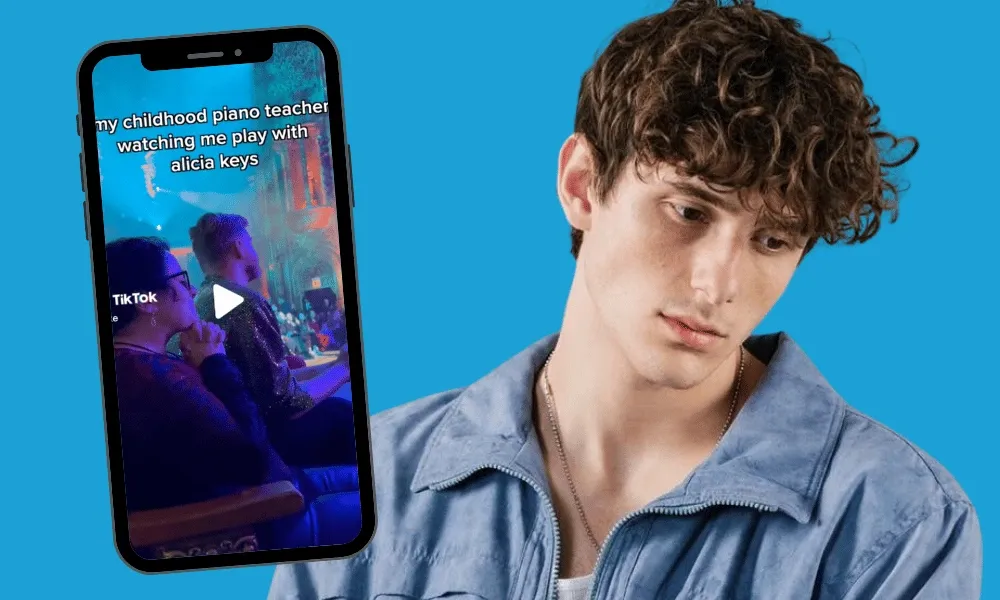 Joven con chaqueta azul sosteniendo un teléfono que muestra un video de TikTok titulado 'mi profesor de piano de la infancia viéndome tocar con Alicia Keys'.